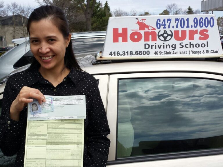 Honours student holding a road test result beside the school car