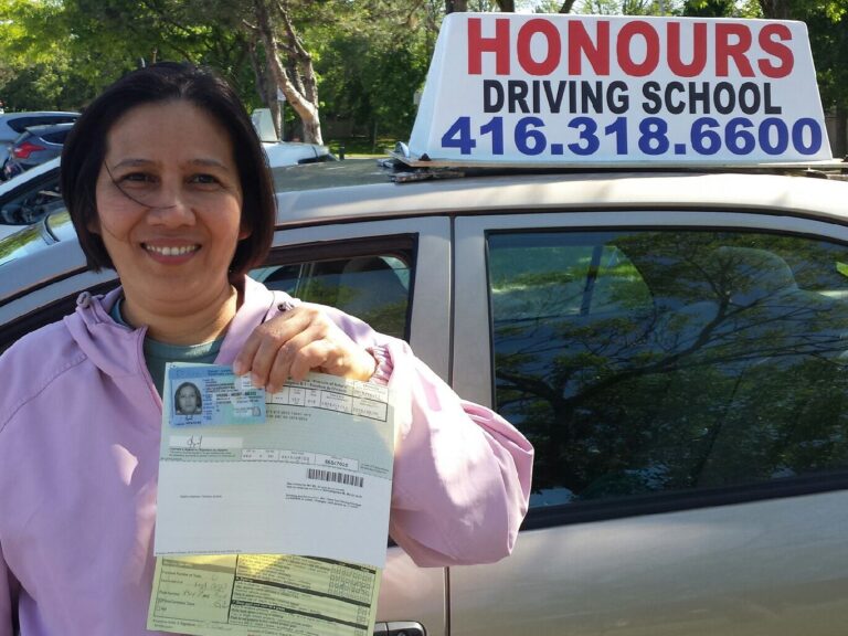 Honours student holding a road test result beside the school car